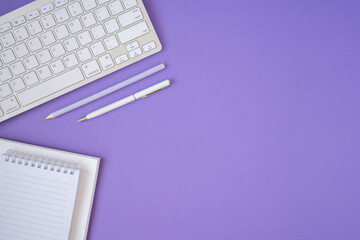 Creative flat lay photo of workspace desk, purple background. Keyboard, notepad, pen and pencil. Flat lay, Top view