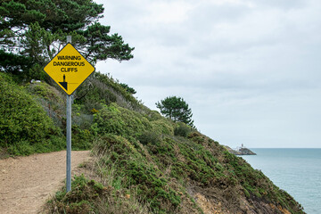 Ein gelbes Schild, das vor steilen Klippen warnt