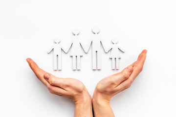 Hands holding wooden figures of family. Care and protection concept