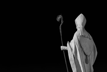 Catholic Church. Bishop with mitre and crosier, an old white marble statue on Lucca old walls, erected in the 17th century (Black and White with copy space) - obrazy, fototapety, plakaty