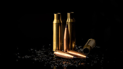 Isolate on a black background, macro photo of a bullet with a ballistic tip and cartridge cases, powder is scattered, soft focus - obrazy, fototapety, plakaty