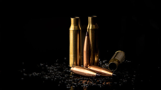 Isolate on a black background, macro photo of a bullet with a ballistic tip and cartridge cases, powder is scattered, soft focus