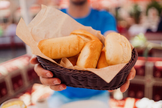 Male hands holding a basket with fresh bread to be served on table. Beautiful food