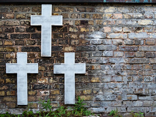 three white crosses on a brick wall