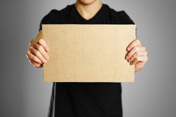 A young guy in a black t-shirt holding a piece of cardboard. Prepared for your text