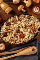 Risotto ai funghi, mushroom risotto, rustic rice with mushrooms, overhead shot on a dark wooden background