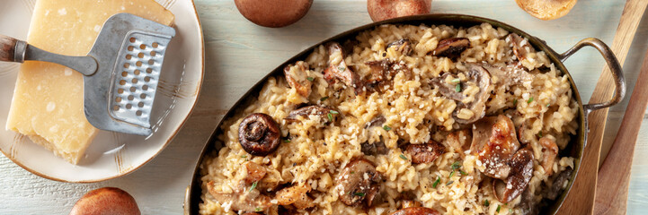 Mushroom risotto, rustic rice dish panorama, with ingredients, shot from the top on a wooden background