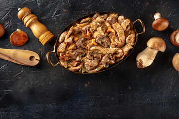 Mushroom beef stroganoff, traditional Russian food. Ragout with meat and fungi, with cream sauce, shot from the top on a black background