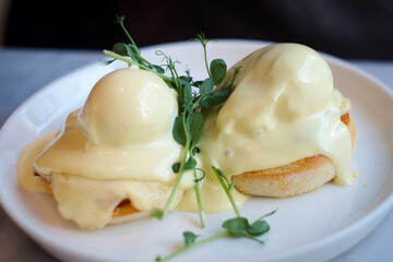 Eggs Benedict is a common American breakfast or brunch dish, consisting of two halves of an English muffin, each topped with Canadian bacon, a poached egg, and hollandaise sauce. 