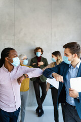 Business colleagues with protective face masks analyzing reports on a meeting in the office.