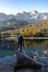 Hiker at Eibsee lake with Zugspitze mountain at sunrise. Sunny outdoor scene in German Alps, Bavaria, Germany, Europe. 