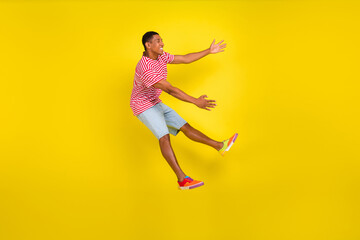 Fototapeta na wymiar Full length profile side photo of guy jump hug big advert wear red striped clothes isolated over yellow color background