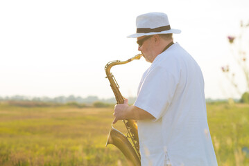 Man playing jazz on saxophone in the spring nature on a sunny day