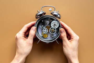 Hands holding alarm clock mechanism with steel gears and wheels close up