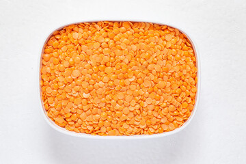 Heap of slip red lentils on a white bowl.