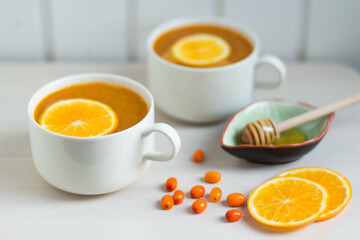 Sea buckthorn tea with orange and honey. White background.