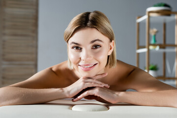 Obraz na płótnie Canvas cheerful young woman lying on massage table
