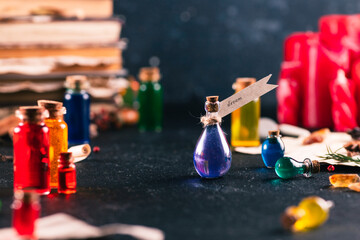 Small bottles with colorful liquids on the table among various magical attributes.
