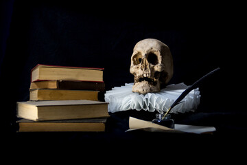Books with a quill, inkwell, skull and gola .on dark background concept of universal literature