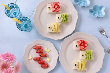 Home made Carp streamer shaped fruits sandwiches. Carp streamer shaped wiener sausage and pink gerbera daisy flowers. Japanese children day table. こいのぼりフルーツサンドイッチとこいのぼりウインナー　こどもの日