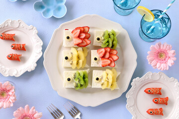 Home made Carp streamer shaped fruits sandwiches. Carp streamer shaped wiener sausage and pink gerbera daisy flowers. Japanese children day table. こいのぼりフルーツサンドイッチとこいのぼりウインナー　こどもの日