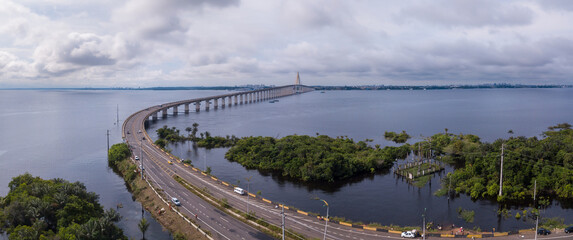 Beautiful drone aerial view of Negro river, trees and bridge "Journalist Phelippe Daou, Ponte Rio Negro" in summer sunny day in Amazon Rainforest. Manaus, Amazonas, Brazil. Concept of nature, ecology.