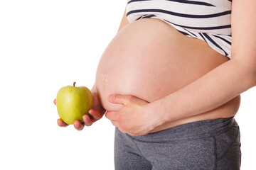 Healthy eating and diet during pregnancy concept - pregnant woman standing and holding green apple near her stomach isolated on white