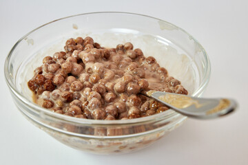 Granola mixed with yogurt in a transparent bowl on a white background. Healthy food.