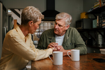 affectionate elderly couple holding hands in kitchen 