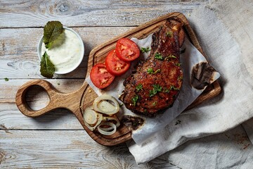 Grilled steak. Appetizing roasted meat with vegetables and herbs. Top view. Copy space. Rustic wooden table background.