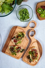 Tasty prosciutto sandwich, fig, cream cheese and herbs on wooden cutting board. Top view