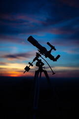 Silhouette of a telescope with colorful skies.