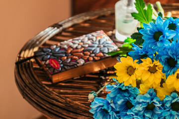 żółto-niebieskie jasne kwiaty na słomianym stole w daczy w ciepłych promieniach jesiennego słońca przerwa na pracę zdalną w domu - obrazy, fototapety, plakaty