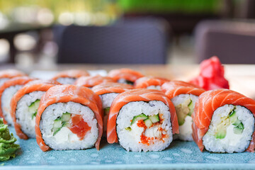 Sushi roll Philadelphia with salmon, smoked eel, avocado, cream cheese on blue plate in the cafe. Sushi menu. Japanese food