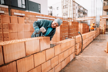 industrial details - Construction bricklayer worker building walls with bricks, mortar and rubber...