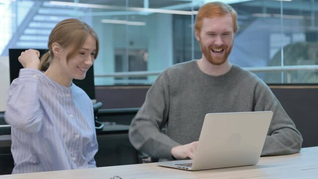Young Man and Woman Celebrating Success on Laptop 