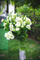 White vase with flowers in a restaurant, served table. Basket with flowers, kibana, wedding floristry.