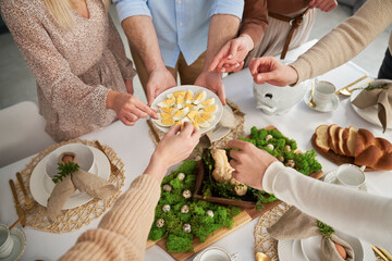 Top view of unrecognizable family sharing with egg during easter dinner