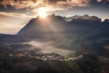 Obraz premium Aerial view of sunrise over Doi Luang Chiang Dao mountain range with foggy and local village on hill in tropical rainforest at Ban Na Lao Mai