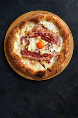 Carbonara pizza with bacon and egg on dark stone background