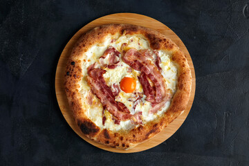 Carbonara pizza with bacon and egg on dark stone background