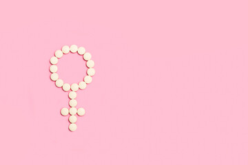 Signo femenino hecho con pastillas pildoras sobre un fondo rosa liso y aislado. Vista superior y de...