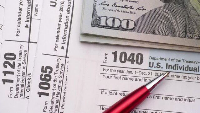 Tax Form 1040, 1120, 1065 and dollar bills, close up.