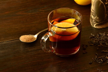 Chinese black tea, pu-erh tea in a glass cup with lemon on a dark wooden background, copy space