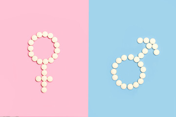 Signo femenino y masculino hecho con pastillas pildoras sobre un fondo de color rosa y celeste liso y aislado Vista superior. Copy space - obrazy, fototapety, plakaty