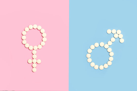 Signo femenino y masculino hecho con pastillas pildoras sobre un fondo de color rosa y celeste liso y aislado Vista superior. Copy space