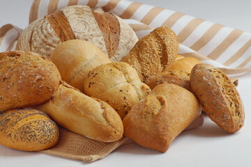 different types of freshly baked delicious bread with a beautiful bright and crispy crust are cut on a kitchen towel on the table