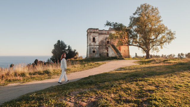 Beautiful girl in white dress enters an ancient castle in the countryside 
