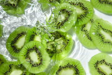 Fototapeta na wymiar Kiwi slices in water on a white background. Peeled and sliced kiwi.