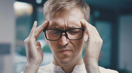 Stressed man having a headache and massaging his temples